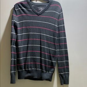 Grey sweater with white and pink stripes.